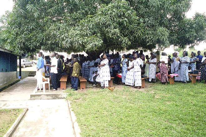 The overflow sits under the mango tree and listens to the service via a PA system - when the electricity is on! - October 2000